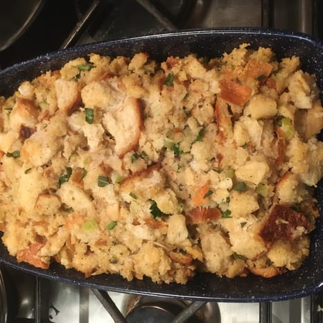 Herb stuffing on a plate with sliced turkey, mashed potatoes, gravy, and green beans