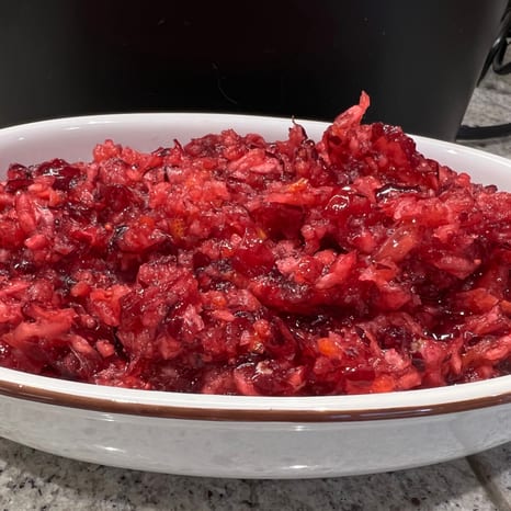 A bowl of whole-berry cranberry sauce beside sliced roast turkey