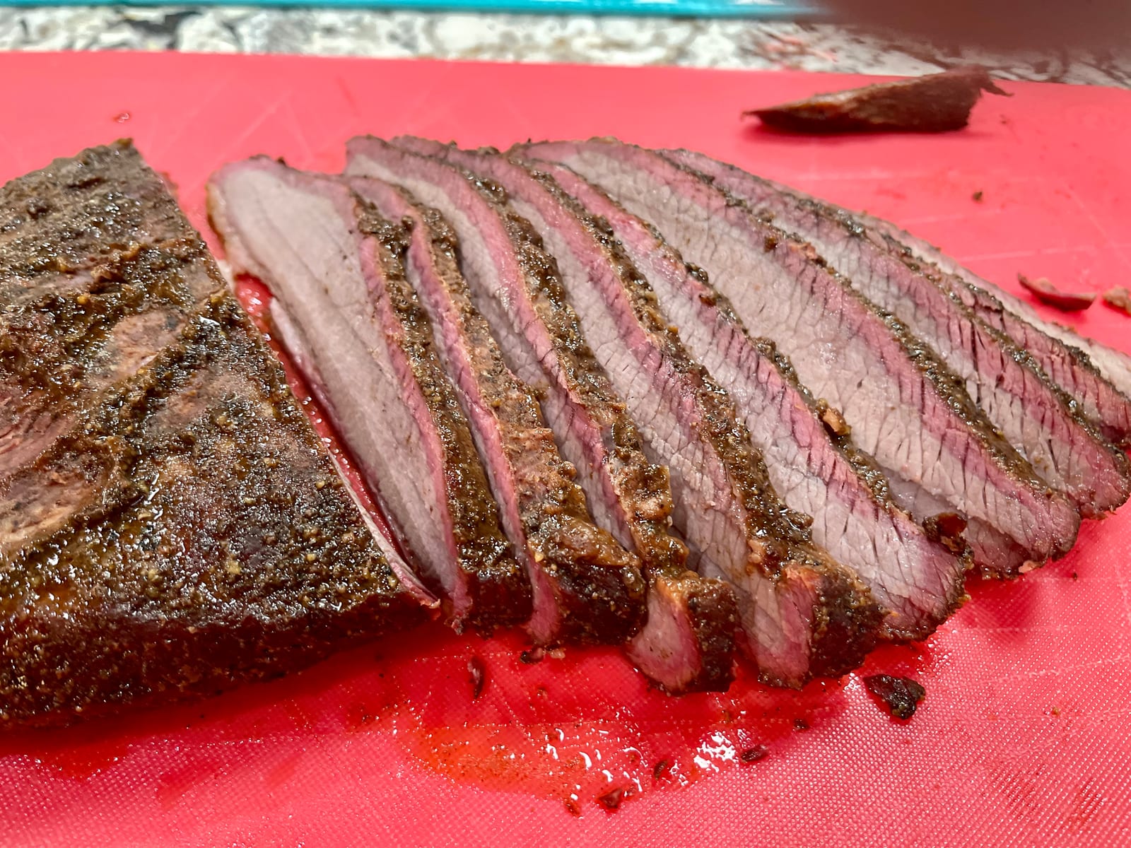 Sliced smoked brisket with a dark bark and a pink ring under the surface
