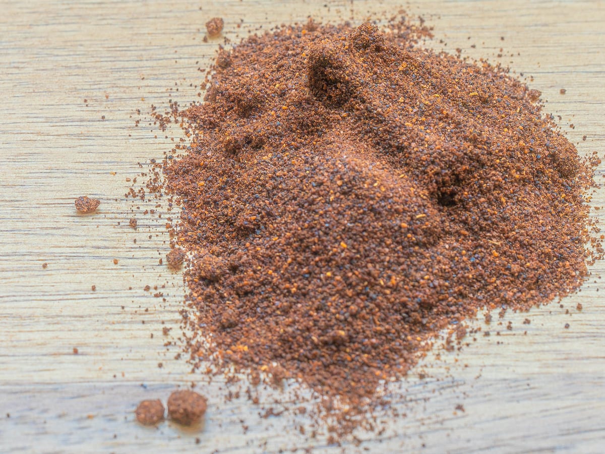 Ground chipotle powder, dark brick red and slightly coarse