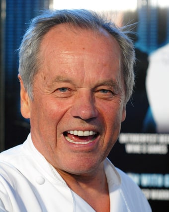 Wolfgang Puck in chef's whites, laughing, photographed at an event in 2012