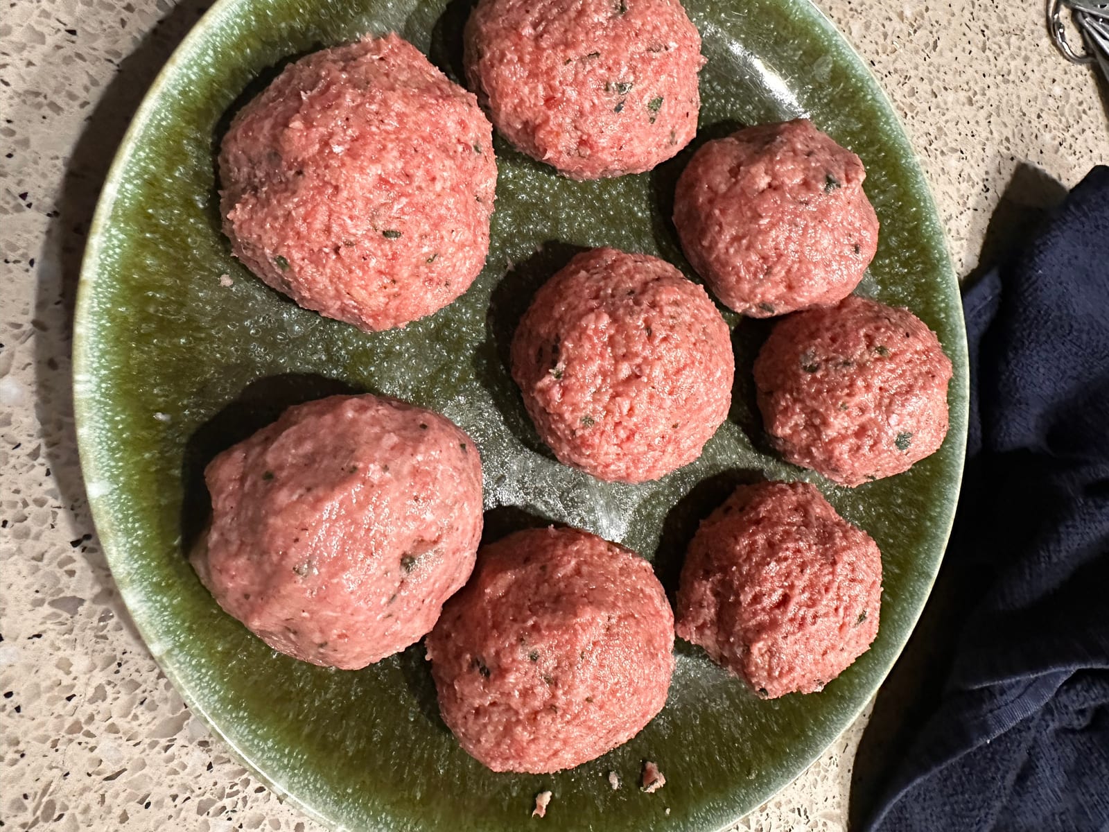 Raw seasoned meatballs resting on a plate before cooking