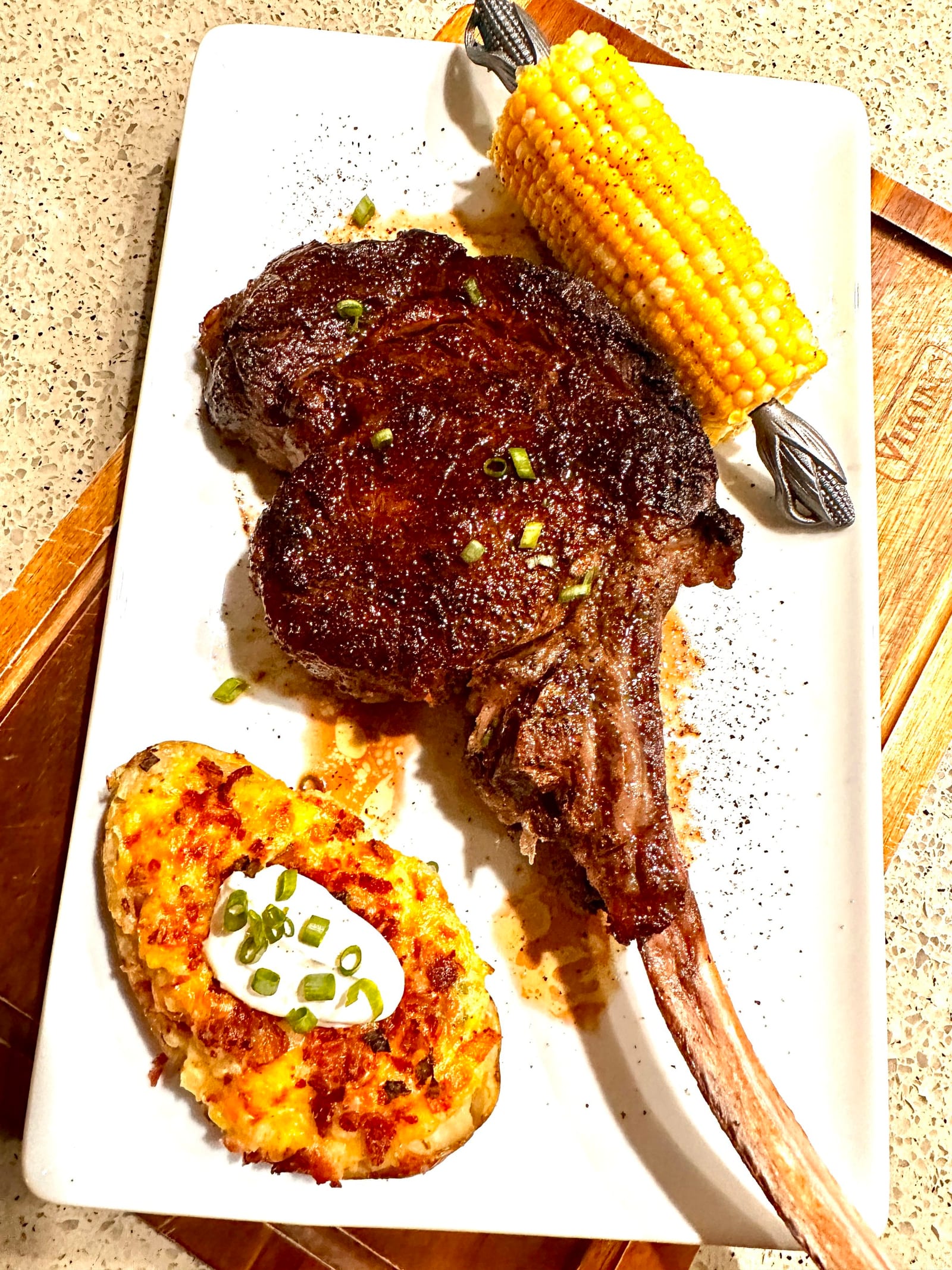 Bone-in steak with charred corn and loaded potato