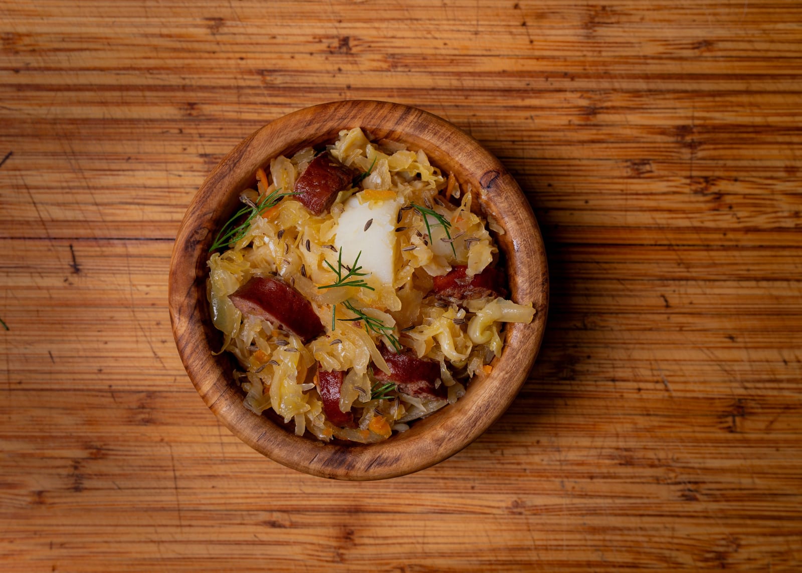 Kapusta (sauerkraut + kielbasa) in wooden bowl on wood