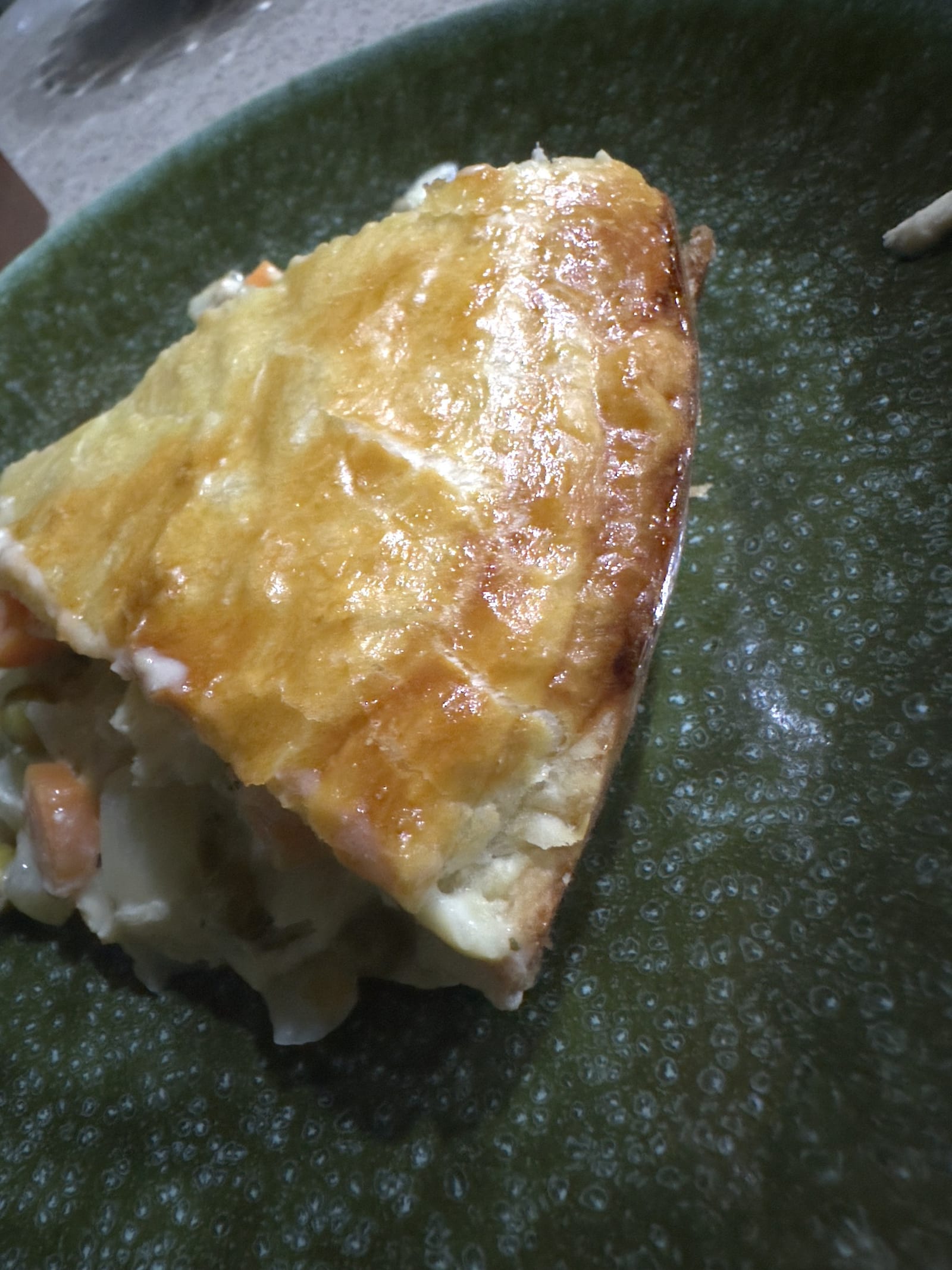 Slice of deep-dish chicken pot pie, flaky baked puff pastry