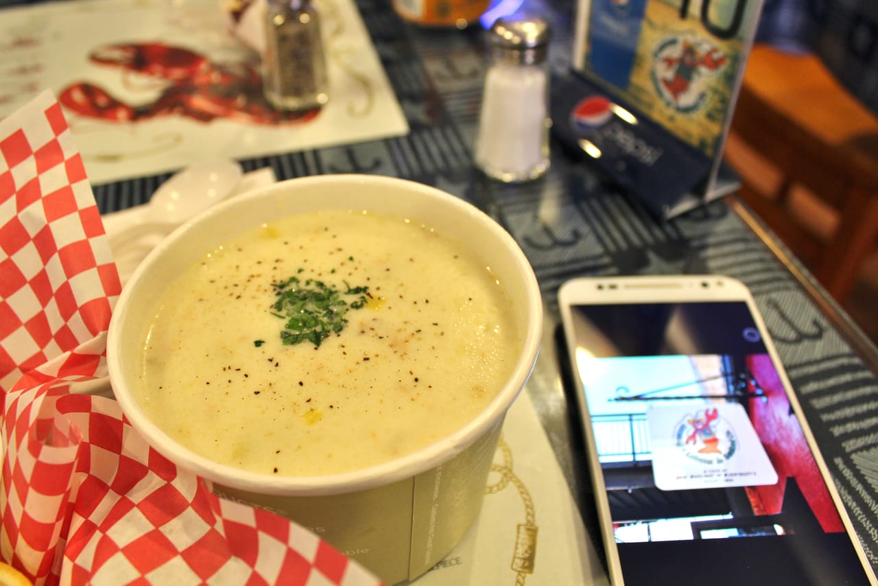 A bowl of creamy New England clam chowder with potato, bacon, and oyster crackers.