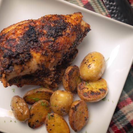 Roasted bone-in chicken breasts with crisp skin on a sheet pan of baby potatoes, lemon, and rosemary