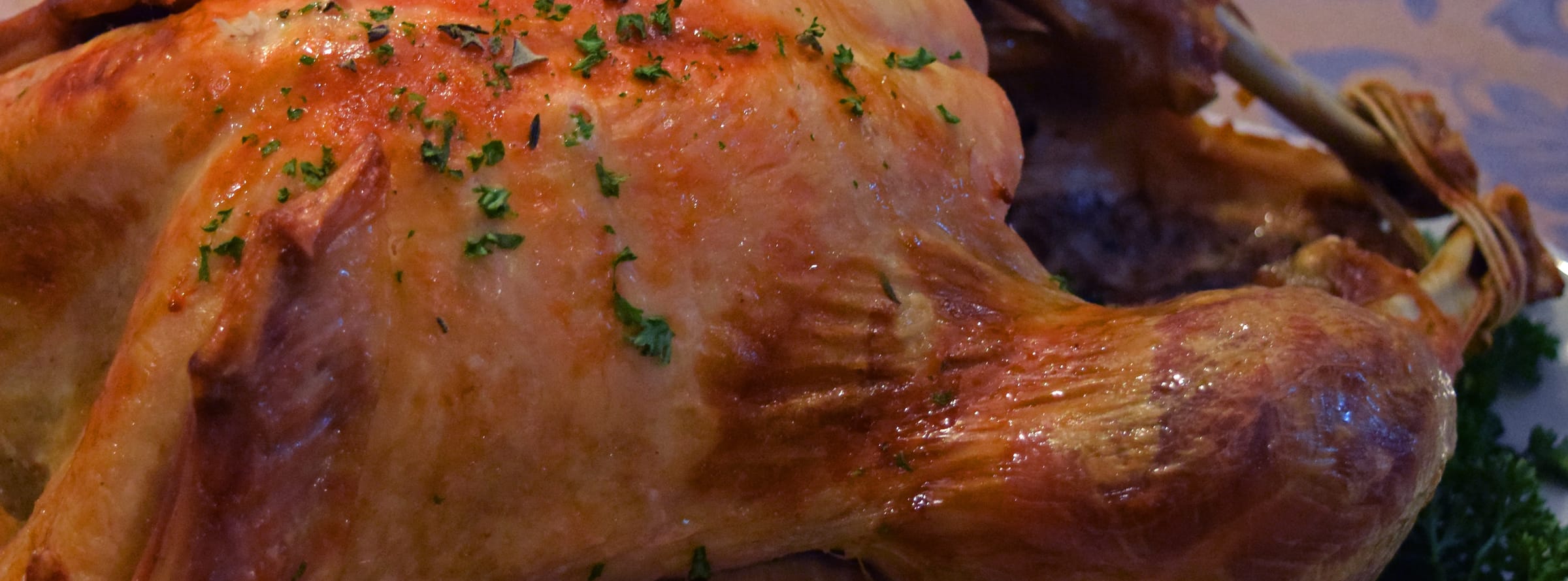 A woman carving a roast turkey on a Thanksgiving table set with pumpkins and side dishes