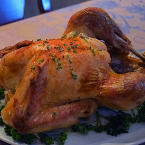 A whole roasted turkey and a glazed ham on a holiday platter with vegetables