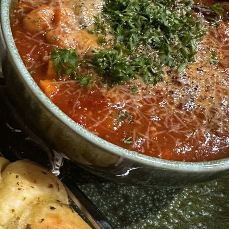 A bowl of creamy white bean chicken chili beside golden cheesy garlic knots